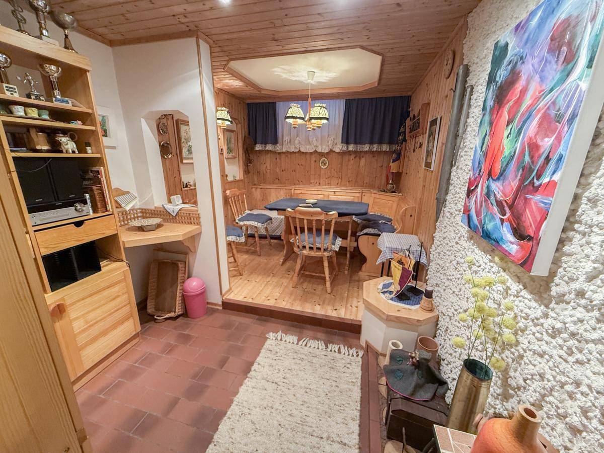 Rustikaler Essbereich mit Holztäfelung, Kachelofen und Terrakottaboden.