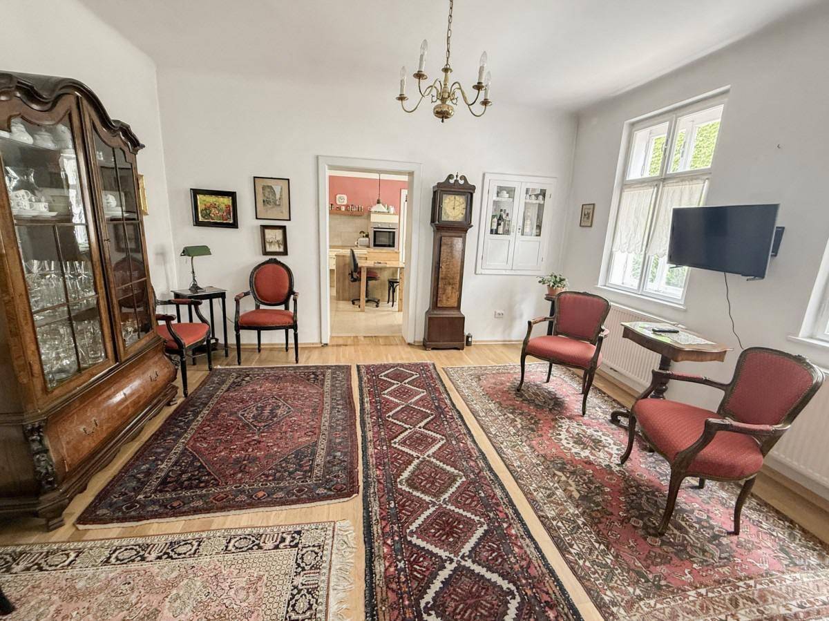 Traditionelles Wohnzimmer mit Holzboden, antiken Möbeln und Blick in die angrenzende Küche.