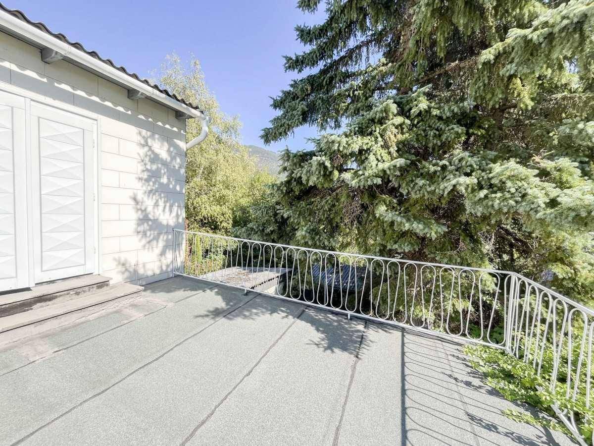 Flachdachterrasse mit Metallgeländer und Blick auf die umliegende grüne Landschaft.
