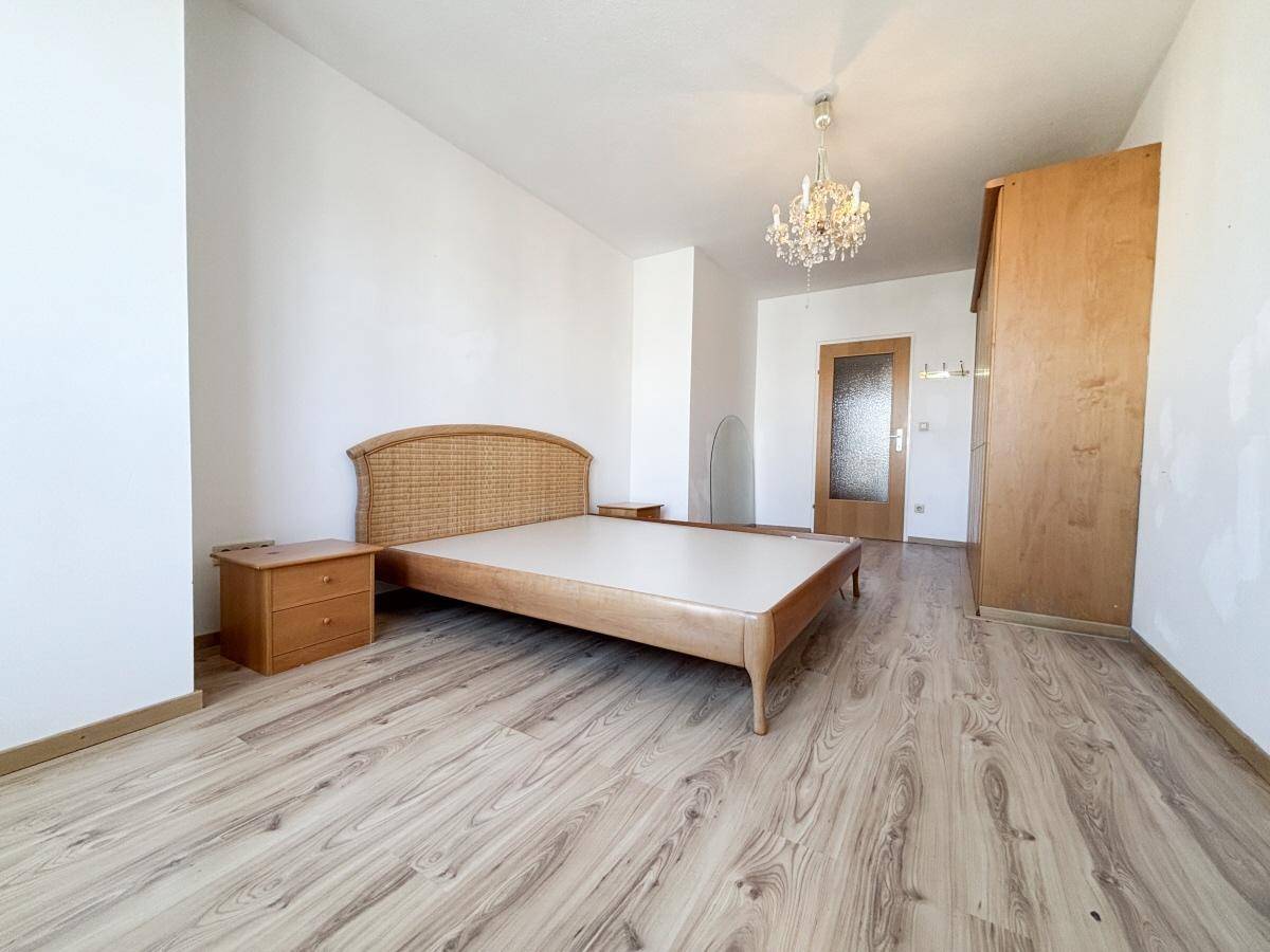 Geräumiges Schlafzimmer mit Laminatboden, Bett und Nachttischen.