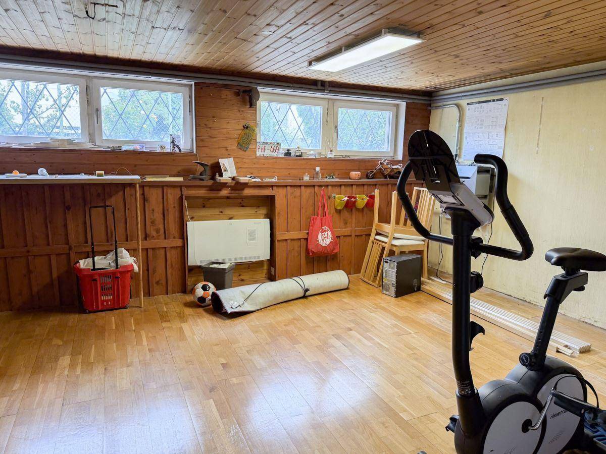 Fitnessraum im Keller mit Holzverkleidung und Trainingsgeräten.