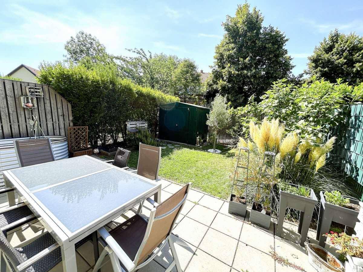 Gepflegter Gartenbereich mit Terrasse, Gartenmöbeln und üppiger Bepflanzung, ideal zum Entspannen.