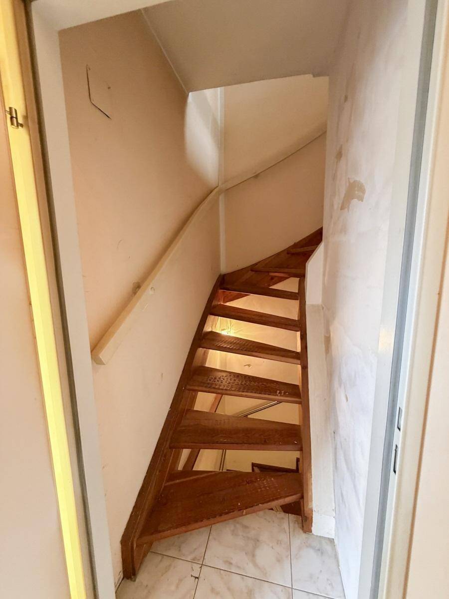 Holztreppe führt in ein oberes Stockwerk, umgeben von hellen Wänden.