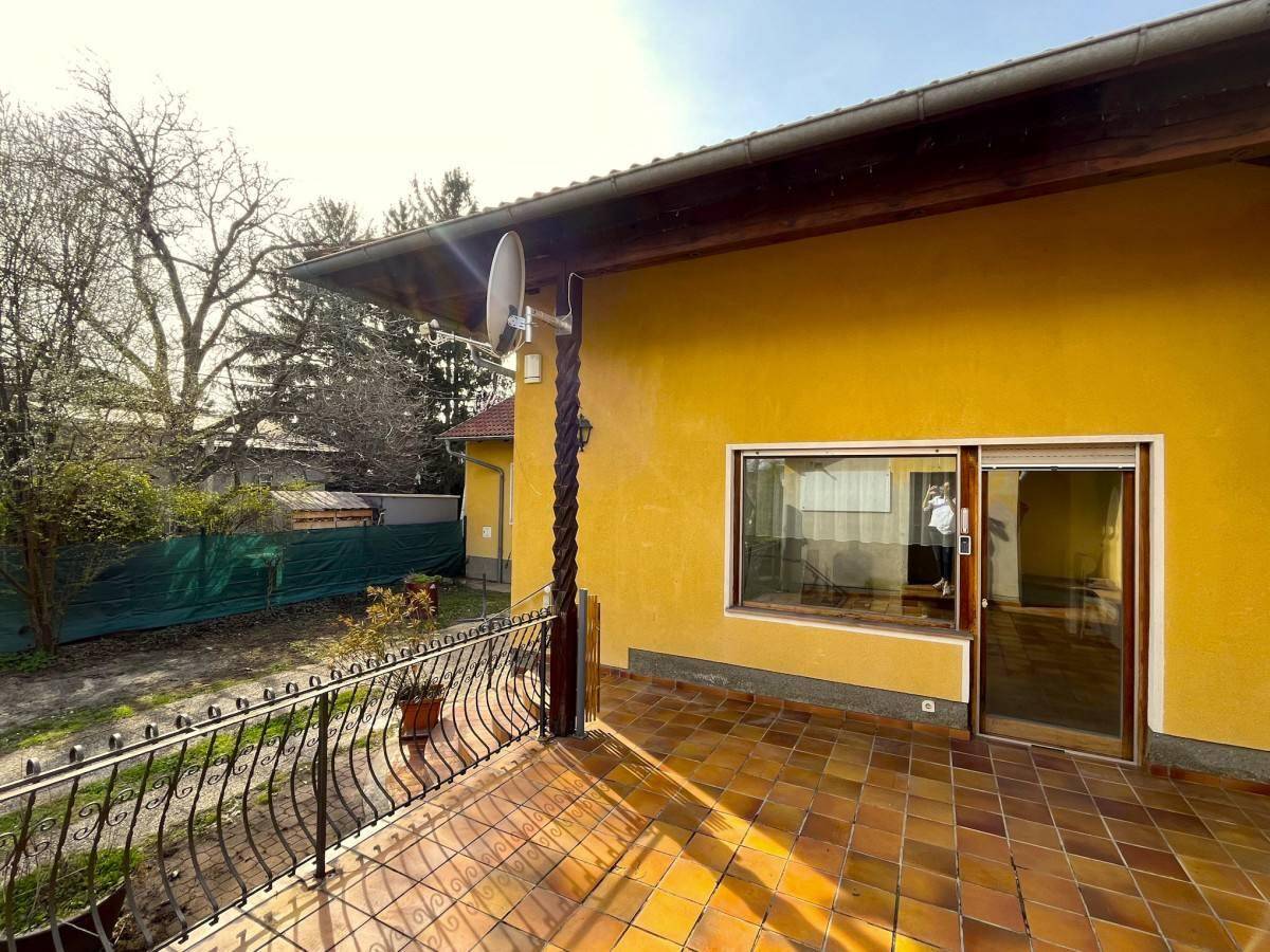 Große geflieste Terrasse mit schmiedeeisernem Geländer und Blick in den Garten.