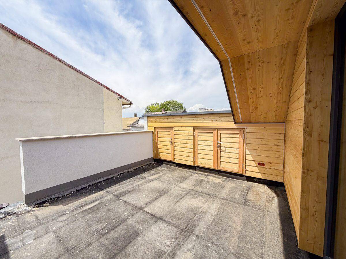 Dachterrasse mit integrierten Holzschränken und Blick auf die Nachbarschaft, ideal für Stauraum.