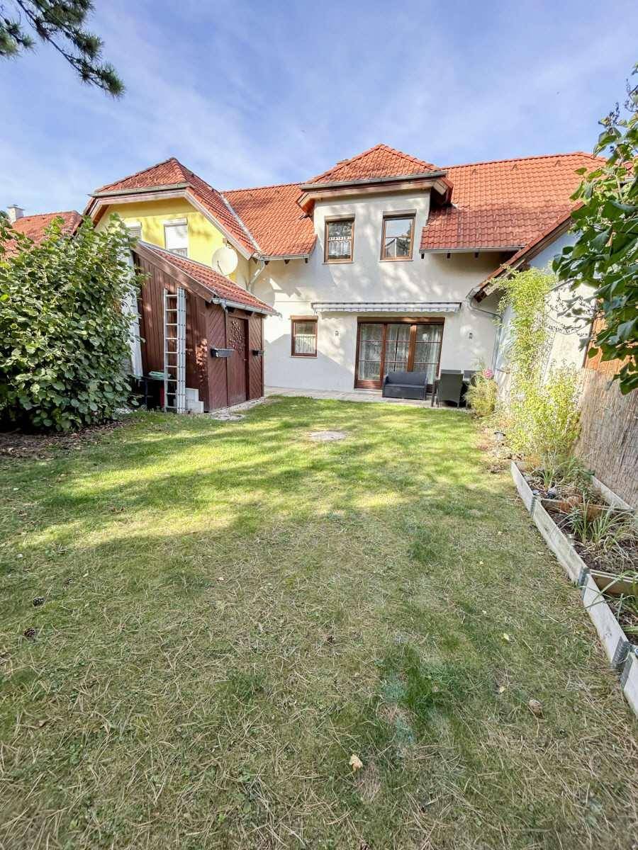 Gepflegter Garten hinter dem Haus mit Rasenfläche und kleiner Gartenhütte.