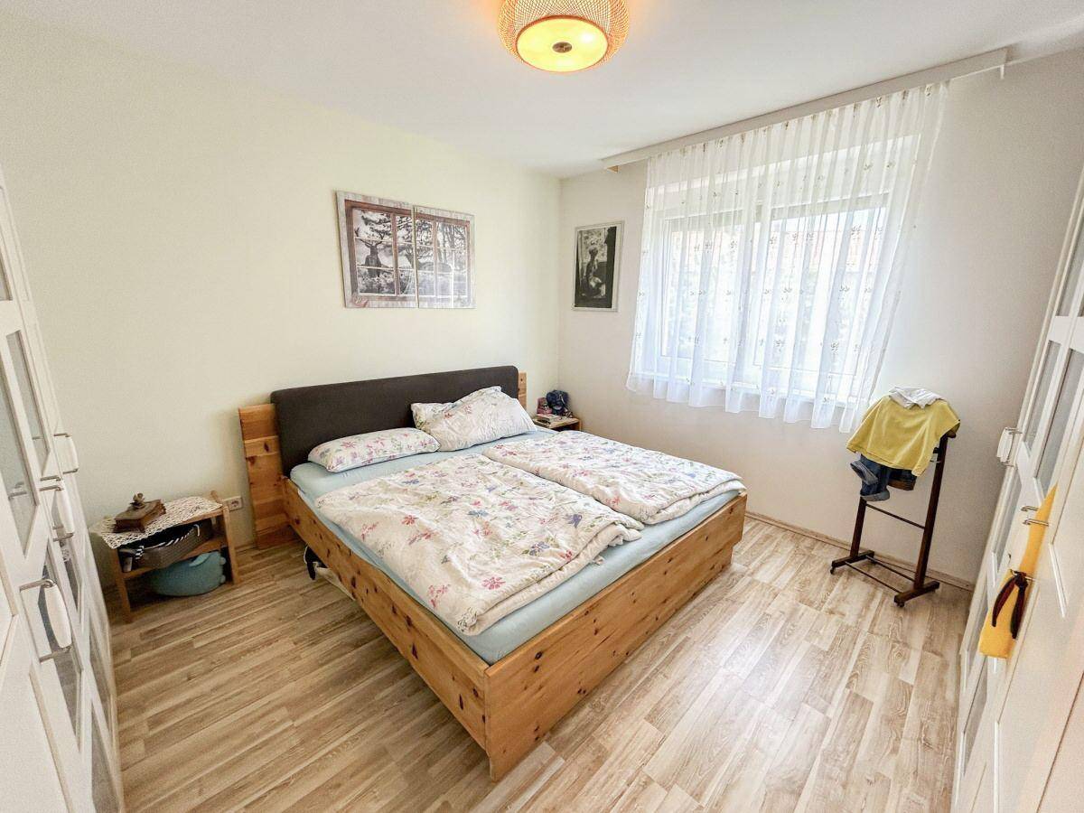 Helles Schlafzimmer mit Doppelbett, Holzboden und großem Fenster für viel Tageslicht.