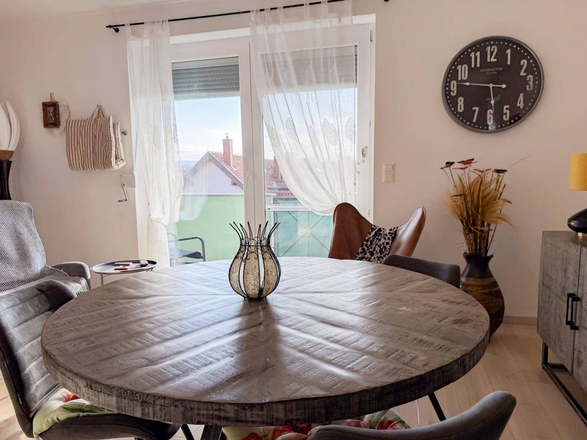 Essbereich mit Holztisch, Stühlen und Zugang zum sonnigen Balkon.