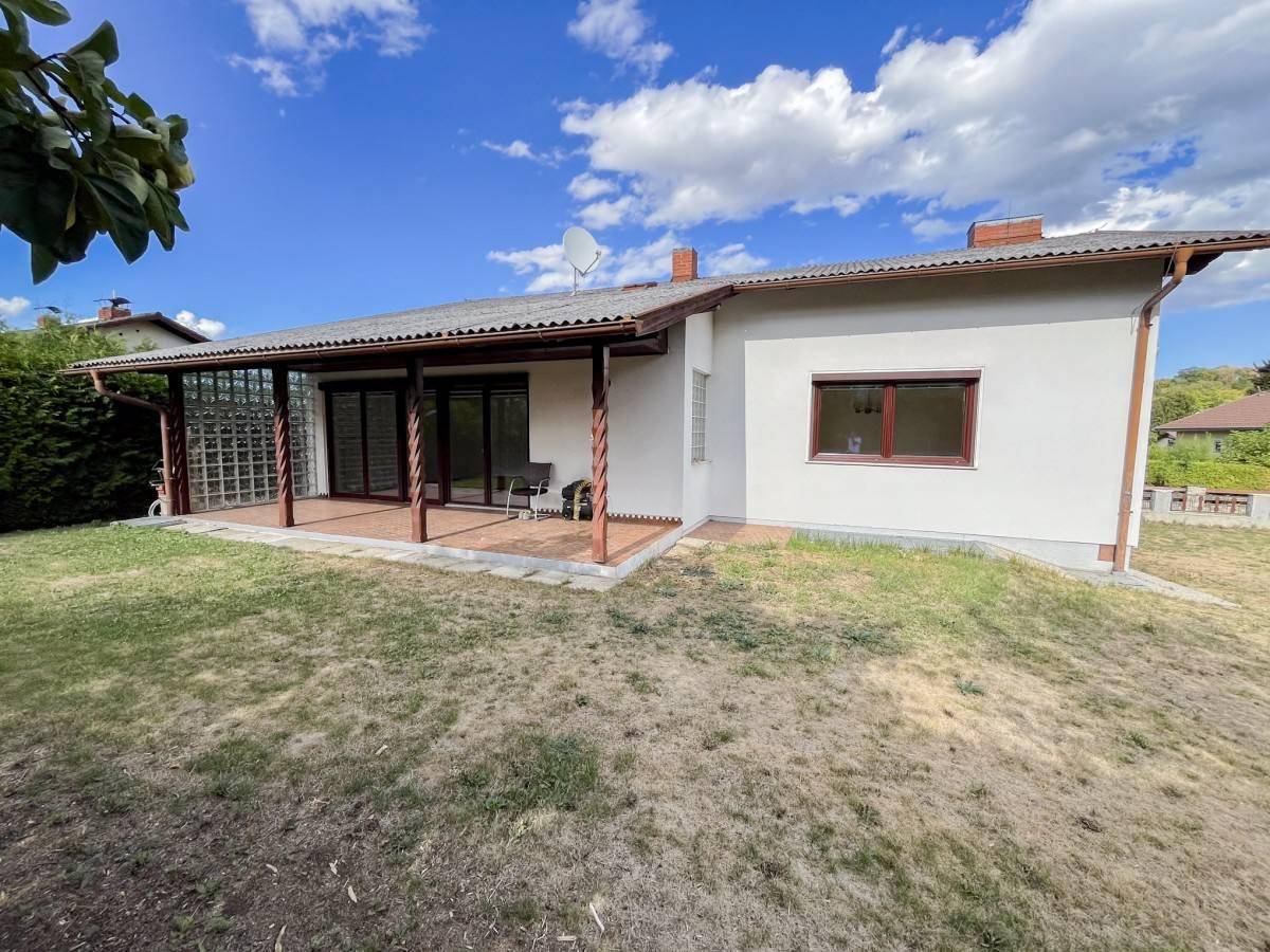 Rückansicht des Hauses mit überdachter Terrasse und weitläufigem Gartenbereich.