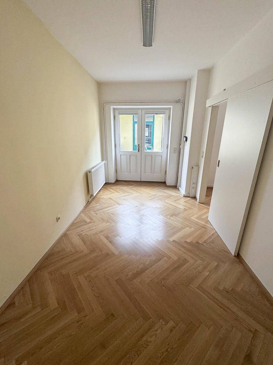 Langer Flur mit Fischgrätparkett und Doppeltüren, die viel natürliches Licht hereinlassen.