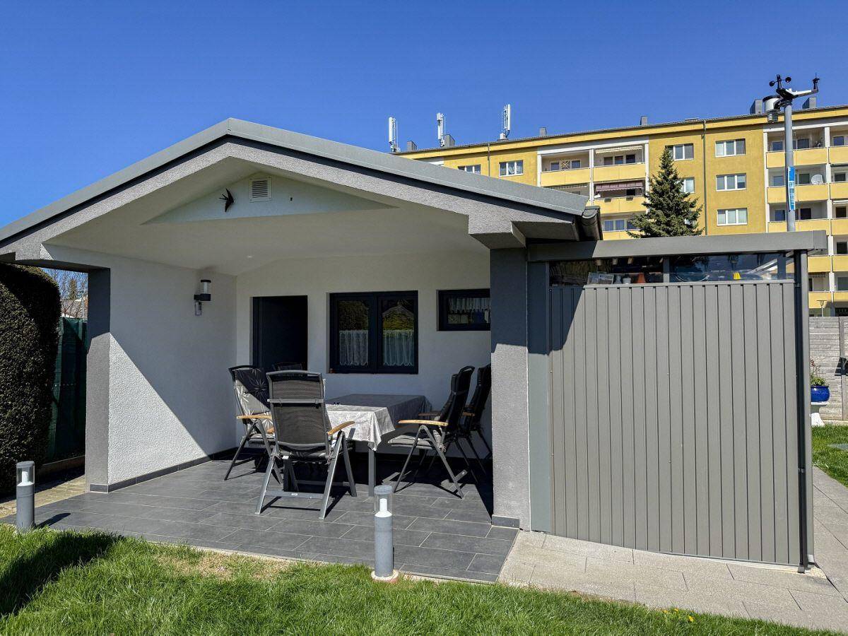 Überdachte Terrasse mit Fliesenboden und Gartenmöbeln, ideal für entspannte Stunden im Freien.