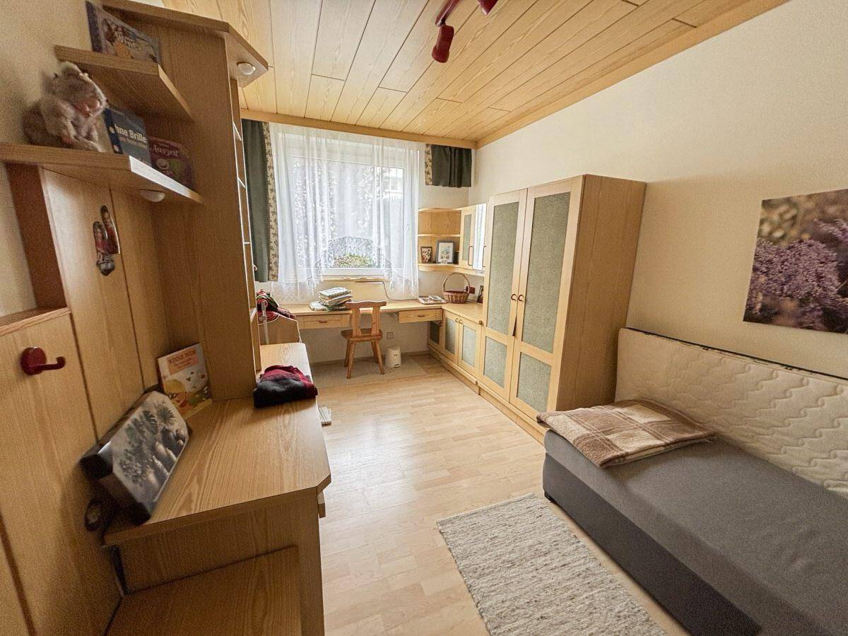 Helles Kinderzimmer mit Holzmöbeln, Schreibtisch und einem gemütlichen Einzelbett.