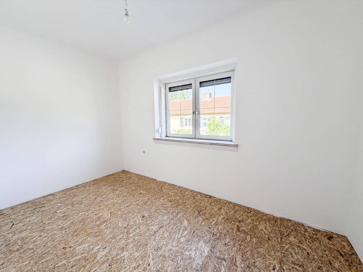 Leerer Raum mit OSB-Plattenboden und Fenster, bereit für den weiteren Ausbau.