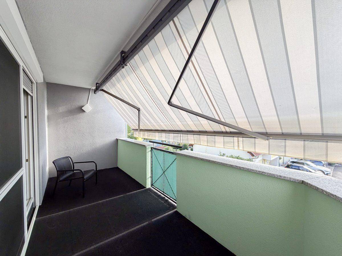 Geräumiger Balkon mit Markise und Blick auf die Umgebung.