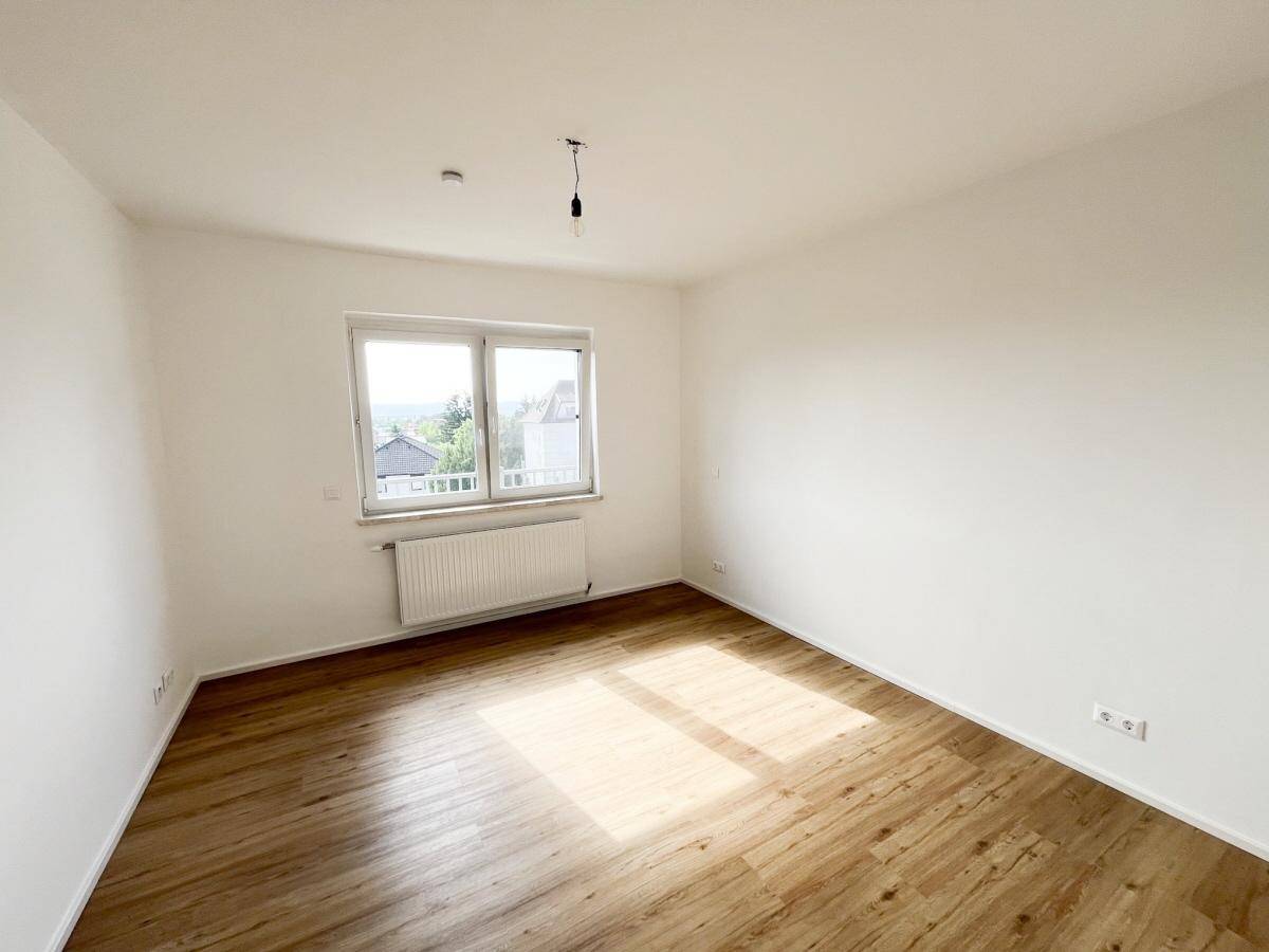Geräumiges Schlafzimmer mit Holzfußboden und großem Fenster für viel Tageslicht.