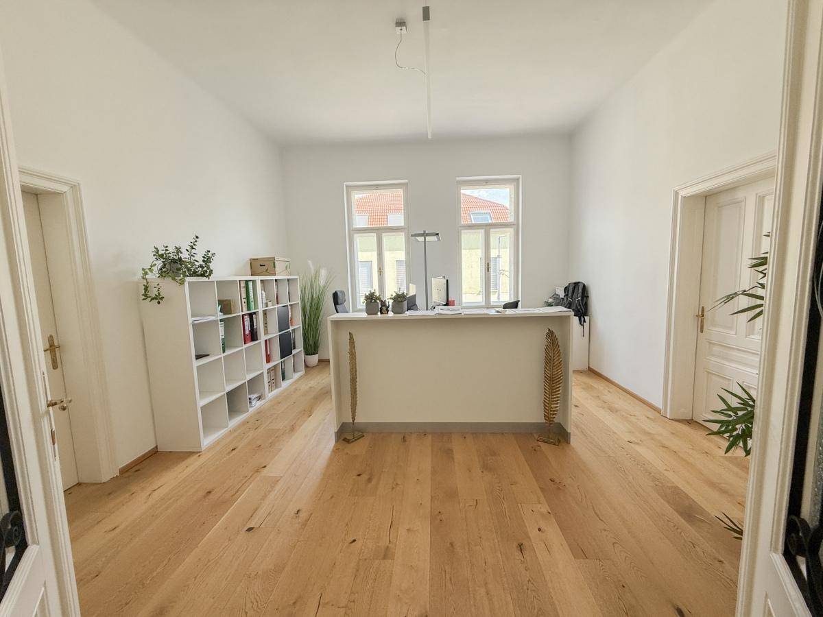 Heller Empfangsbereich oder Großraumbüro mit Holzfußboden, weißen Regalen und viel Tageslicht.