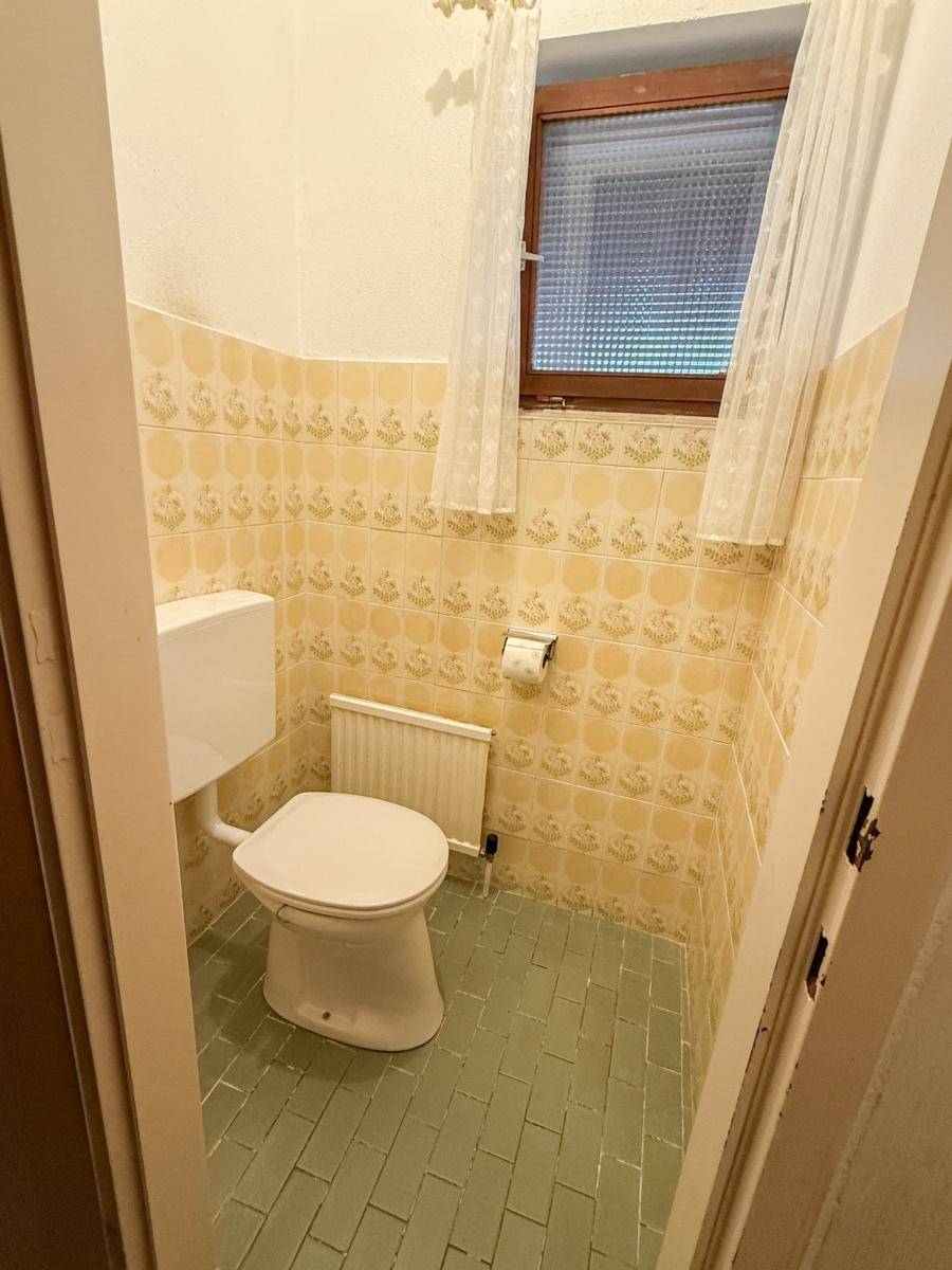 Separate Toilette mit gelben und grünen Fliesen im Retro-Design.