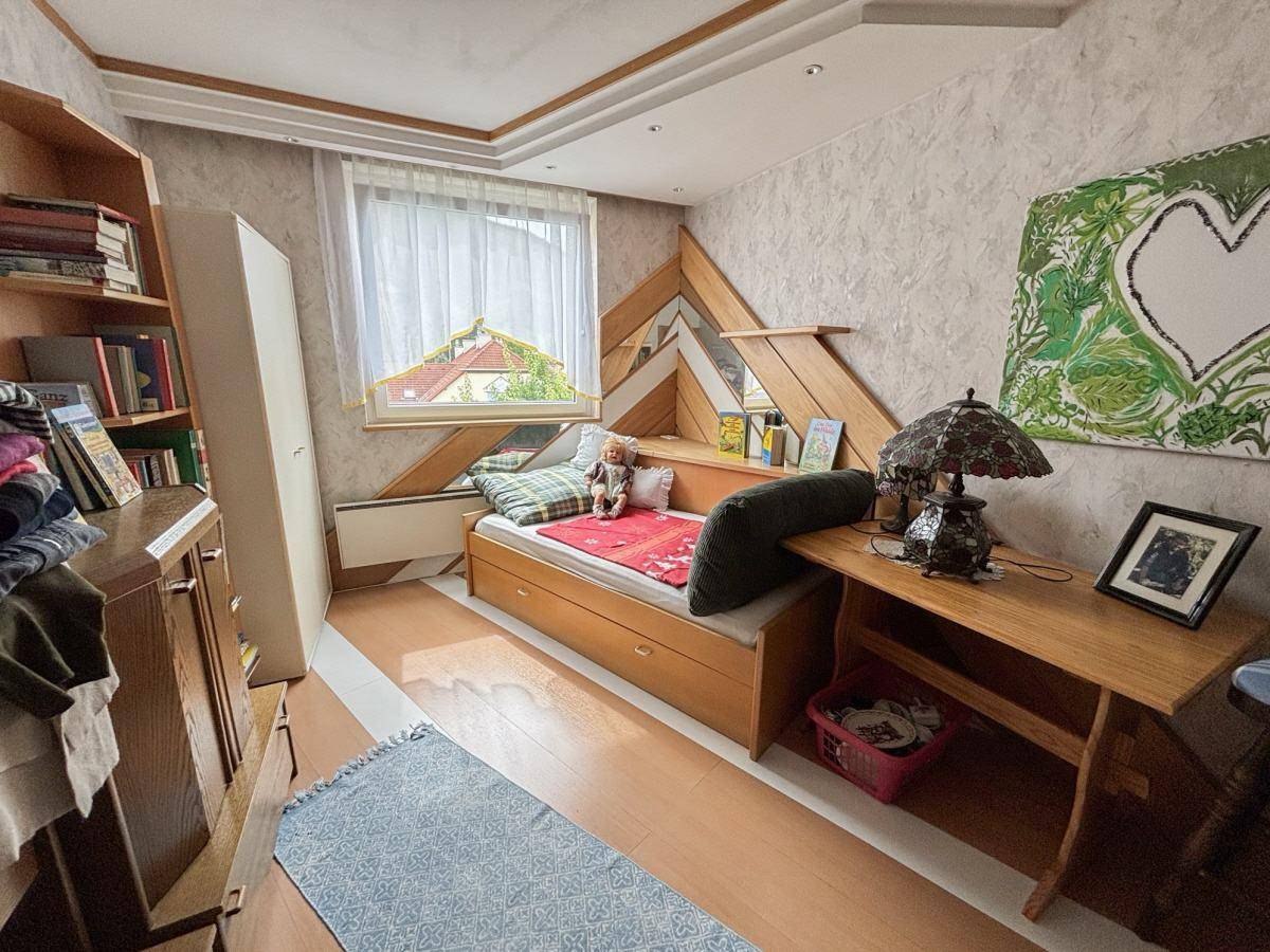 Individuell gestaltetes Schlafzimmer mit Einzelbett, Schreibtisch und kreativer Wanddekoration.