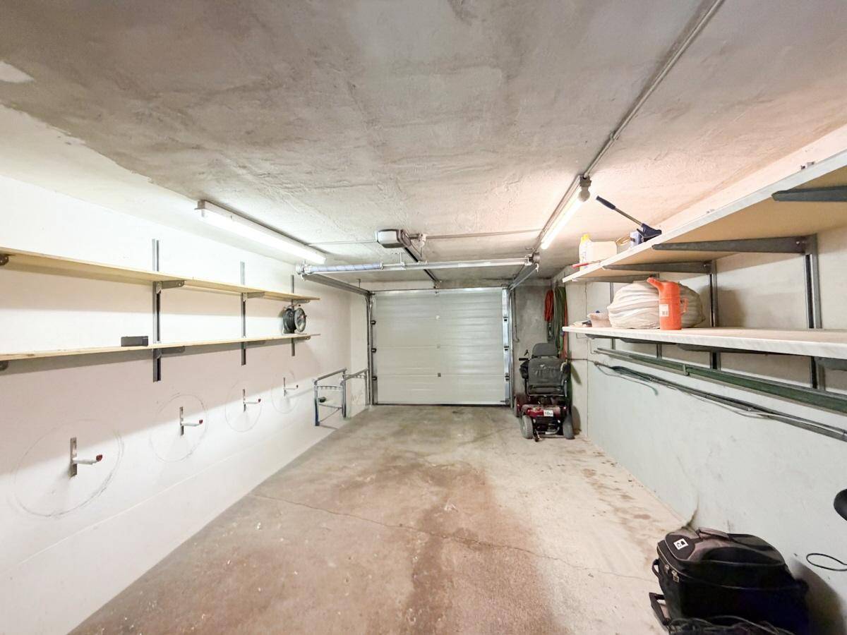 Geräumige Garage mit Rolltor, Regalen und ausreichend Platz für ein Fahrzeug.
