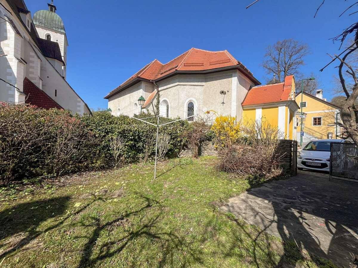 Kleiner Gartenbereich neben einer historischen Kirche mit grünen Hecken und sonnigem Wetter.