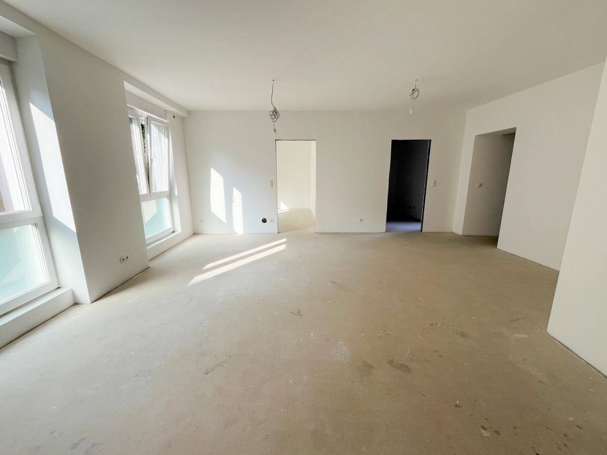 Heller, unmöblierter Raum mit großen Fenstern und viel Tageslicht, bereit für den Ausbau.