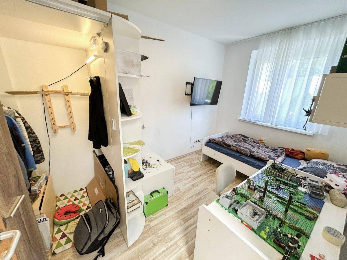 Kinderzimmer mit Einzelbett, Schreibtisch und integriertem Stauraum, ideal für junge Bewohner.