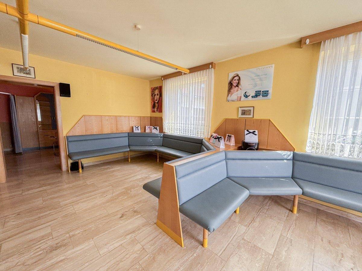 Geräumiges Wartezimmer mit langen Sitzbänken und hellen Fliesen, ideal für Patienten oder Kunden.