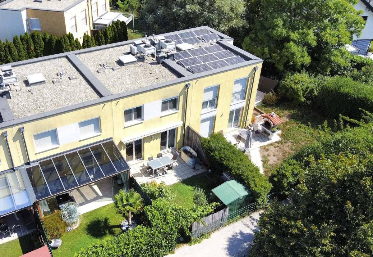 Luftaufnahme von Reihenhäusern mit Gärten, Terrassen und Solaranlagen auf den Dächern.