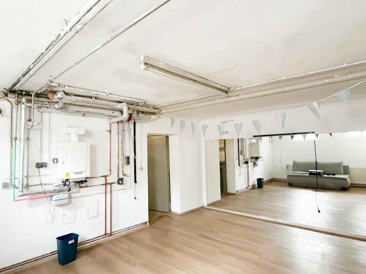 Ausgebauter Kellerraum mit Heizungsanlage, freiliegenden Rohren und Parkettboden.