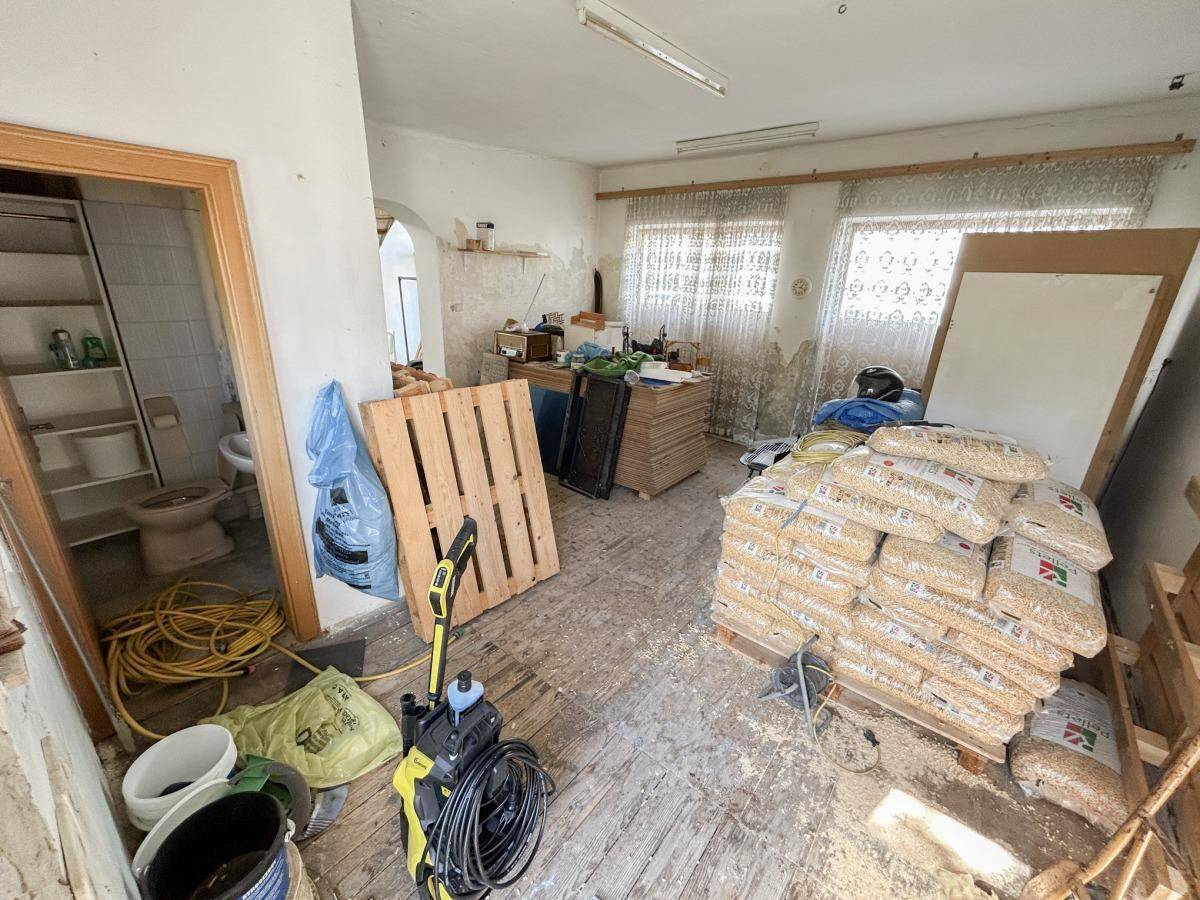 Raum in Renovierung oder als Lager genutzt, mit Holzpelletsäcken und Blick auf eine Toilette.