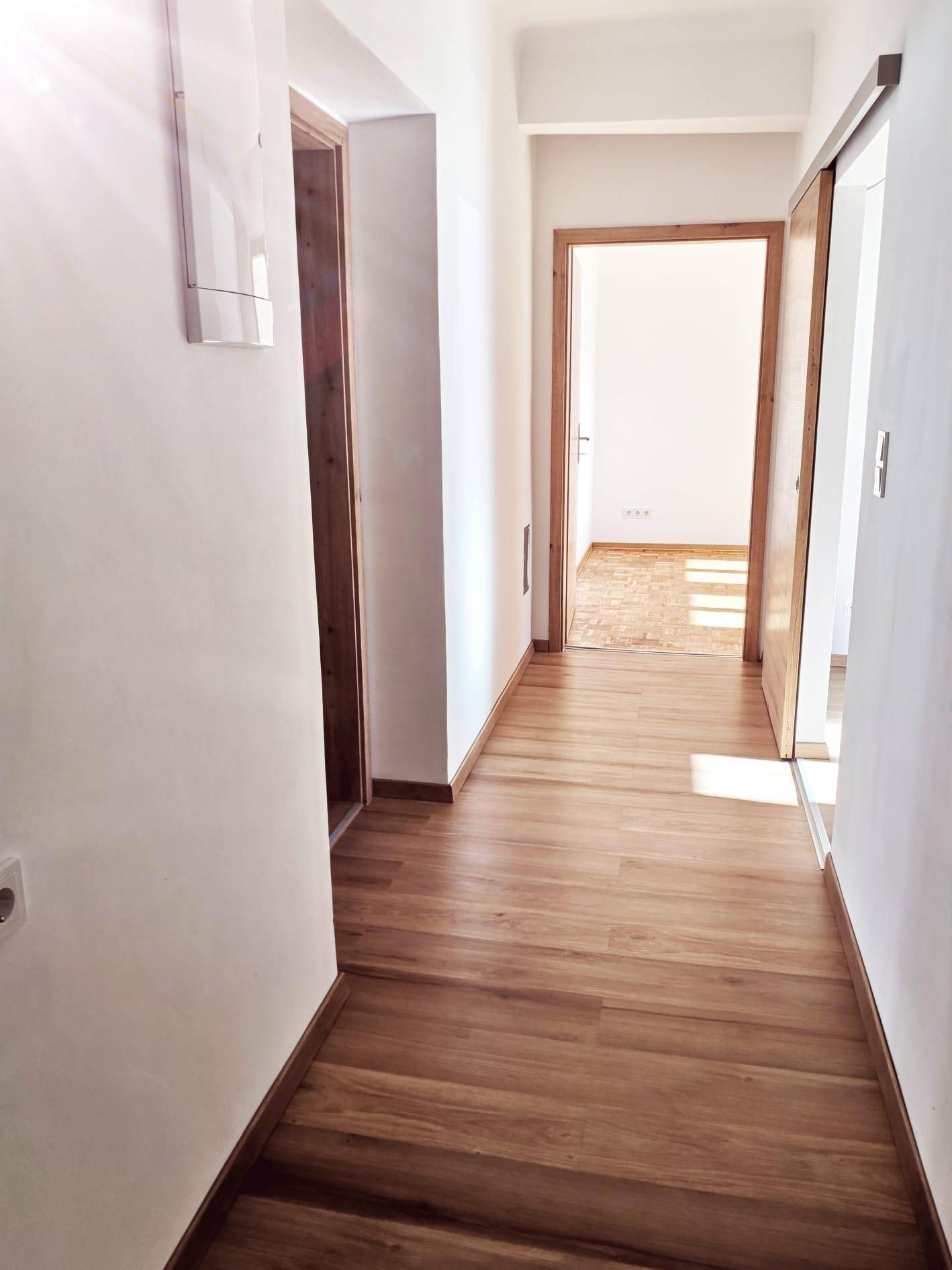 Langer, heller Flur mit Holzboden, der zu verschiedenen Zimmern der Wohnung führt.