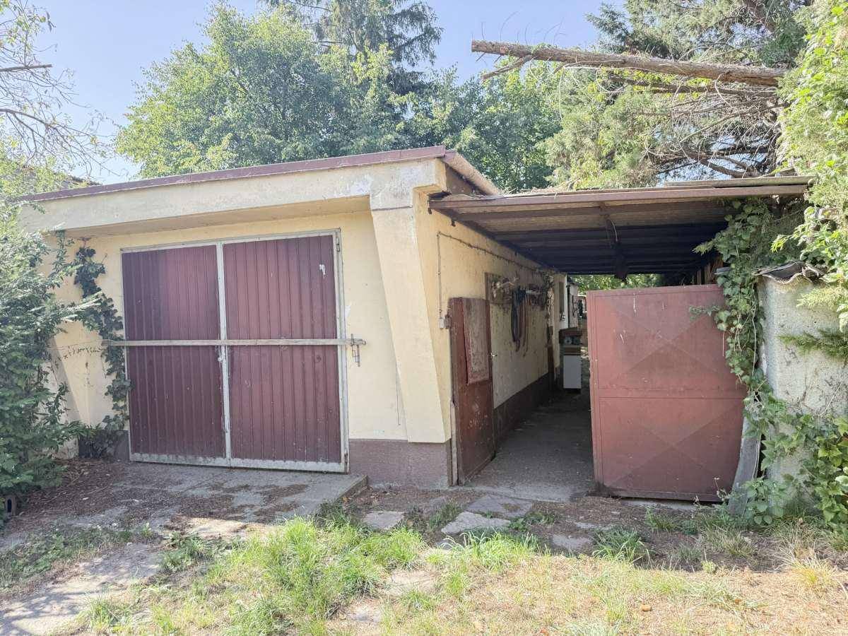 Freistehende Garage mit zwei Toren und angrenzendem überdachtem Bereich.