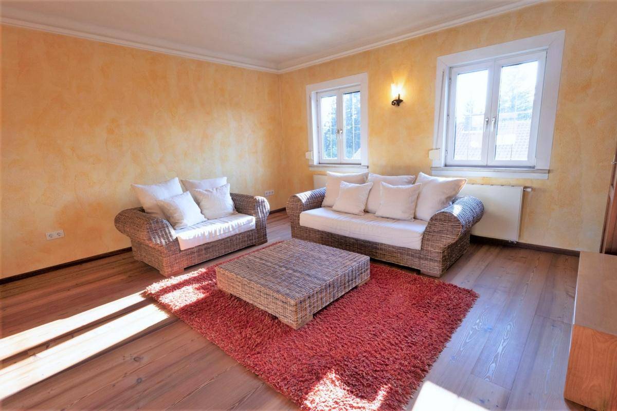 Gemütliches Wohnzimmer mit Korbmöbeln, Holzboden und warmen Wandfarben.