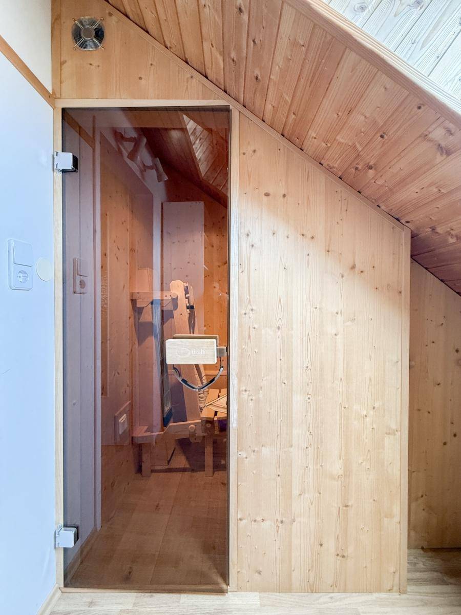 Private Sauna mit Holzverkleidung und Glastür im Dachgeschoss.