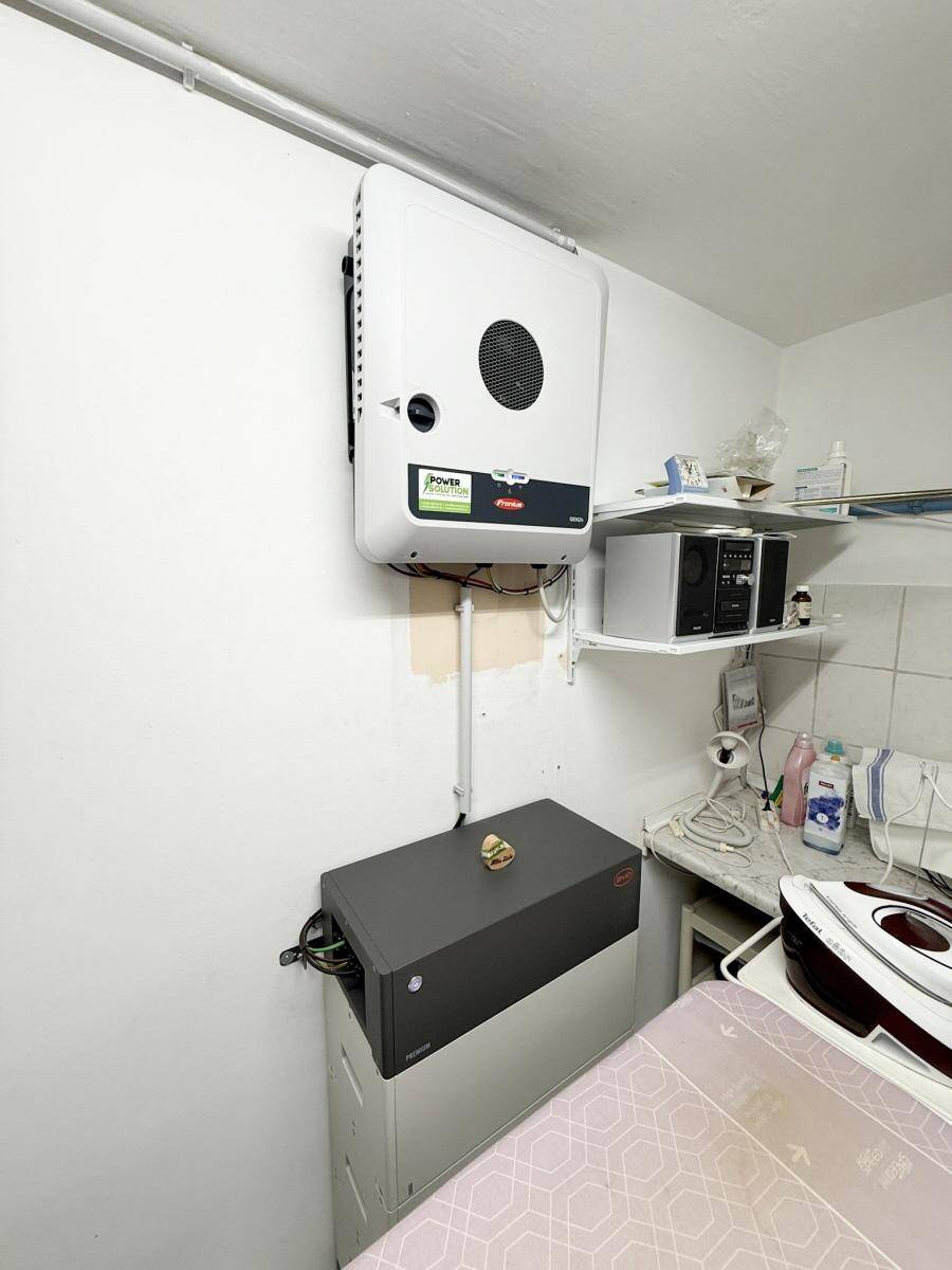 Hauswirtschaftsraum mit Photovoltaik-Wechselrichter, Bügelbrett und Stauraum.