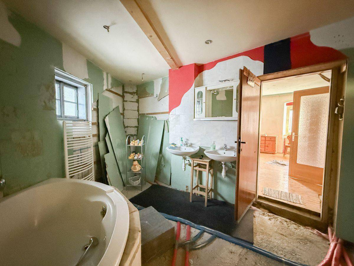 Badezimmer in Renovierung mit zwei Waschbecken, einer Eckbadewanne und einem beheizten Handtuchhalter.