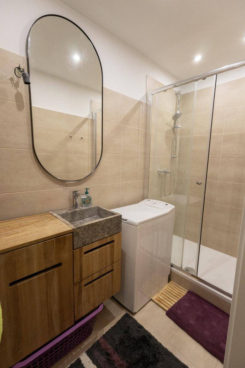 Modernes Badezimmer mit Duschkabine, Waschbecken und integrierter Waschmaschine.