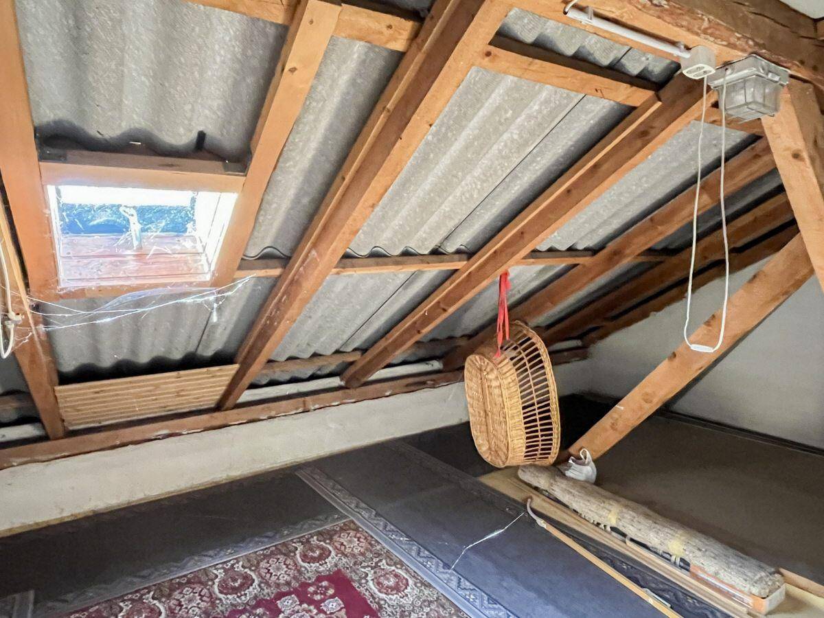 Unausgebauter Dachboden mit sichtbarer Holzkonstruktion und Dachfenster, bietet Ausbaupotenzial.