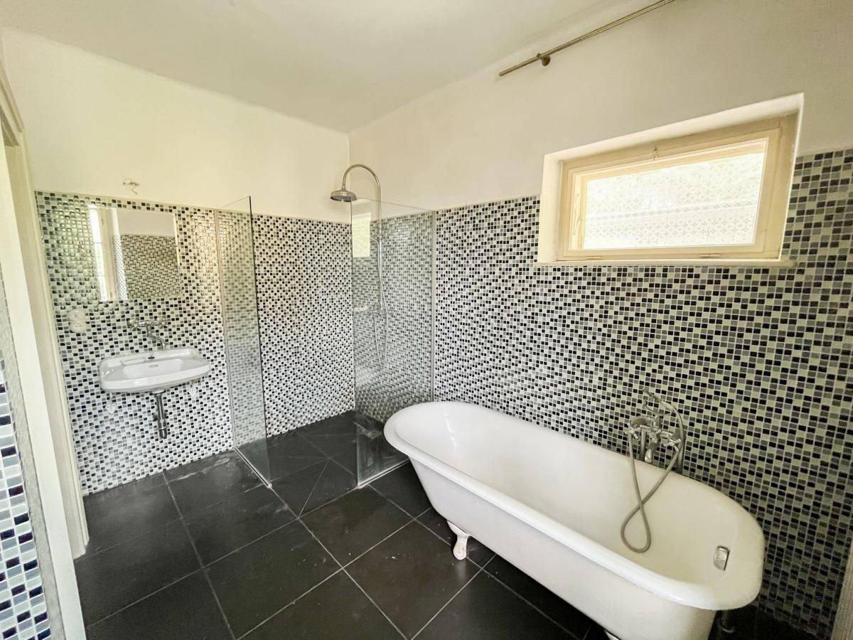 Geräumiges Badezimmer mit freistehender Badewanne, Dusche und Mosaikfliesen.
