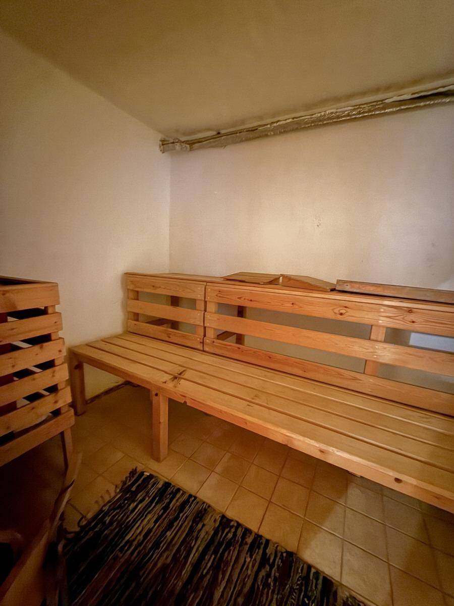 Einfacher Saunaraum im Keller mit Holzbank und Fliesenboden.