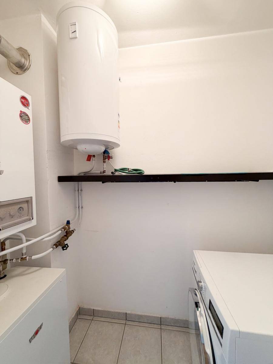 Hauswirtschaftsraum mit Warmwasserboiler, Heizungsanlage und Waschmaschine.