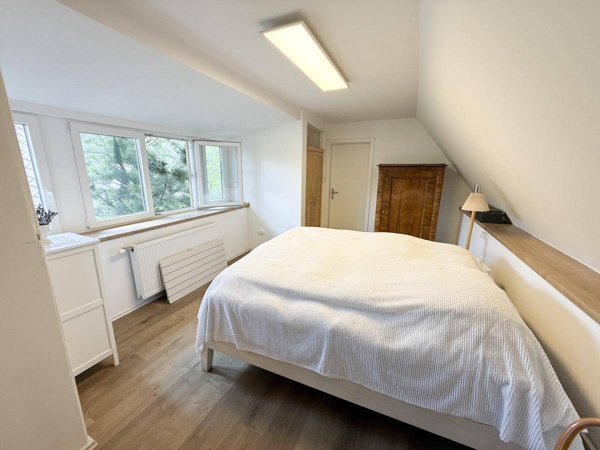 Gemütliches Schlafzimmer im Dachgeschoss mit Laminatboden, Dachschrägen und großen Fenstern.