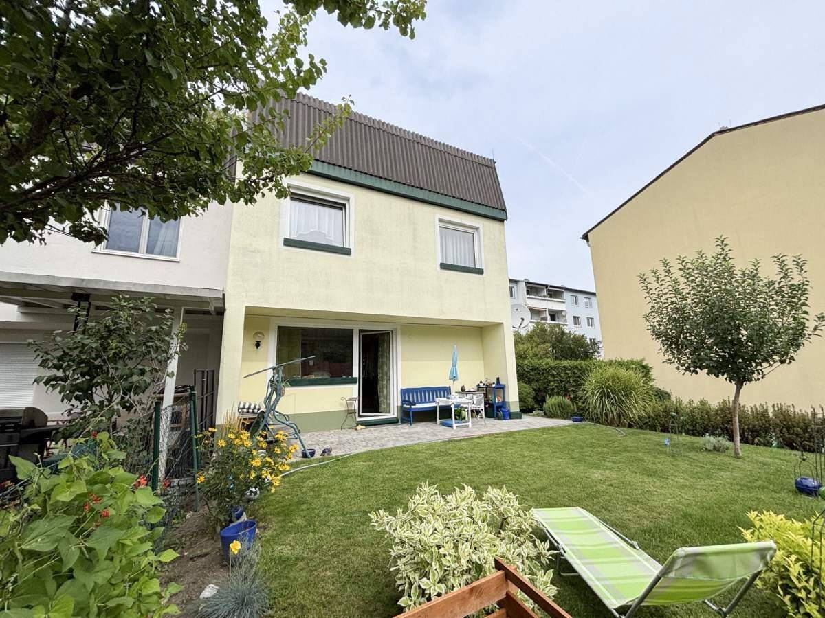 Weitläufiger Gartenbereich mit Rasen, Terrasse und Blick auf die Rückseite des Wohnhauses.