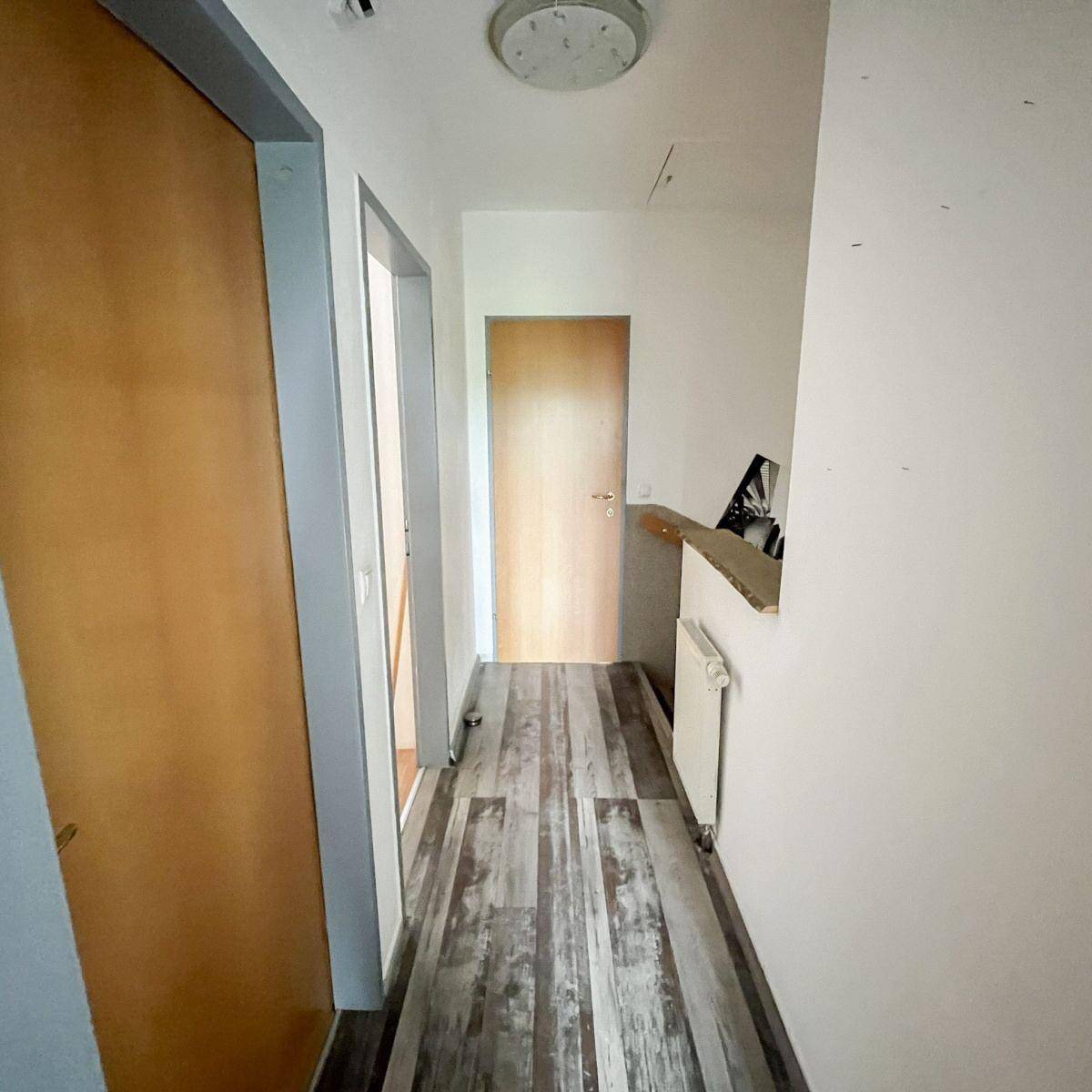 Heller Flur mit Laminatboden und Holztüren, führt zu weiteren Räumen.