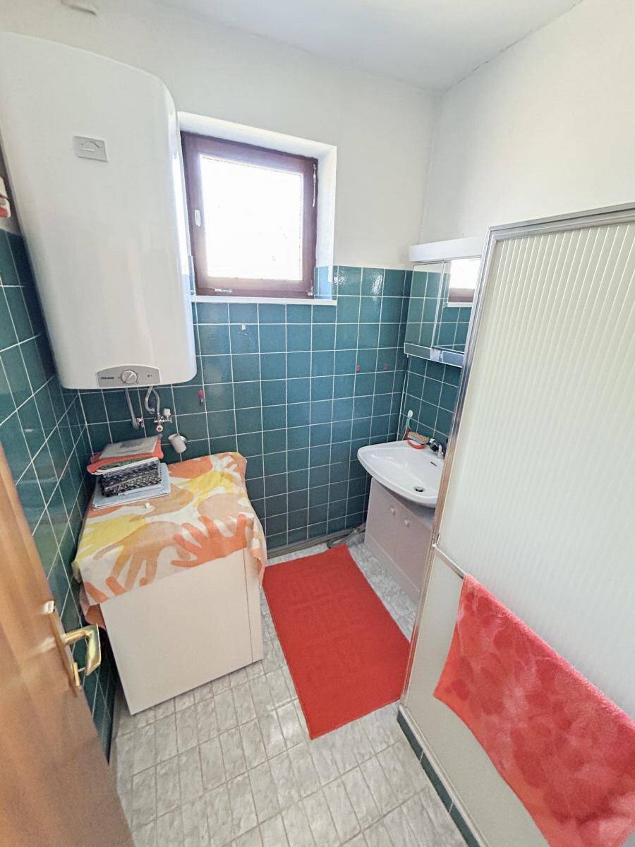 Badezimmer mit blauen Fliesen, Dusche und Fenster für Tageslicht.