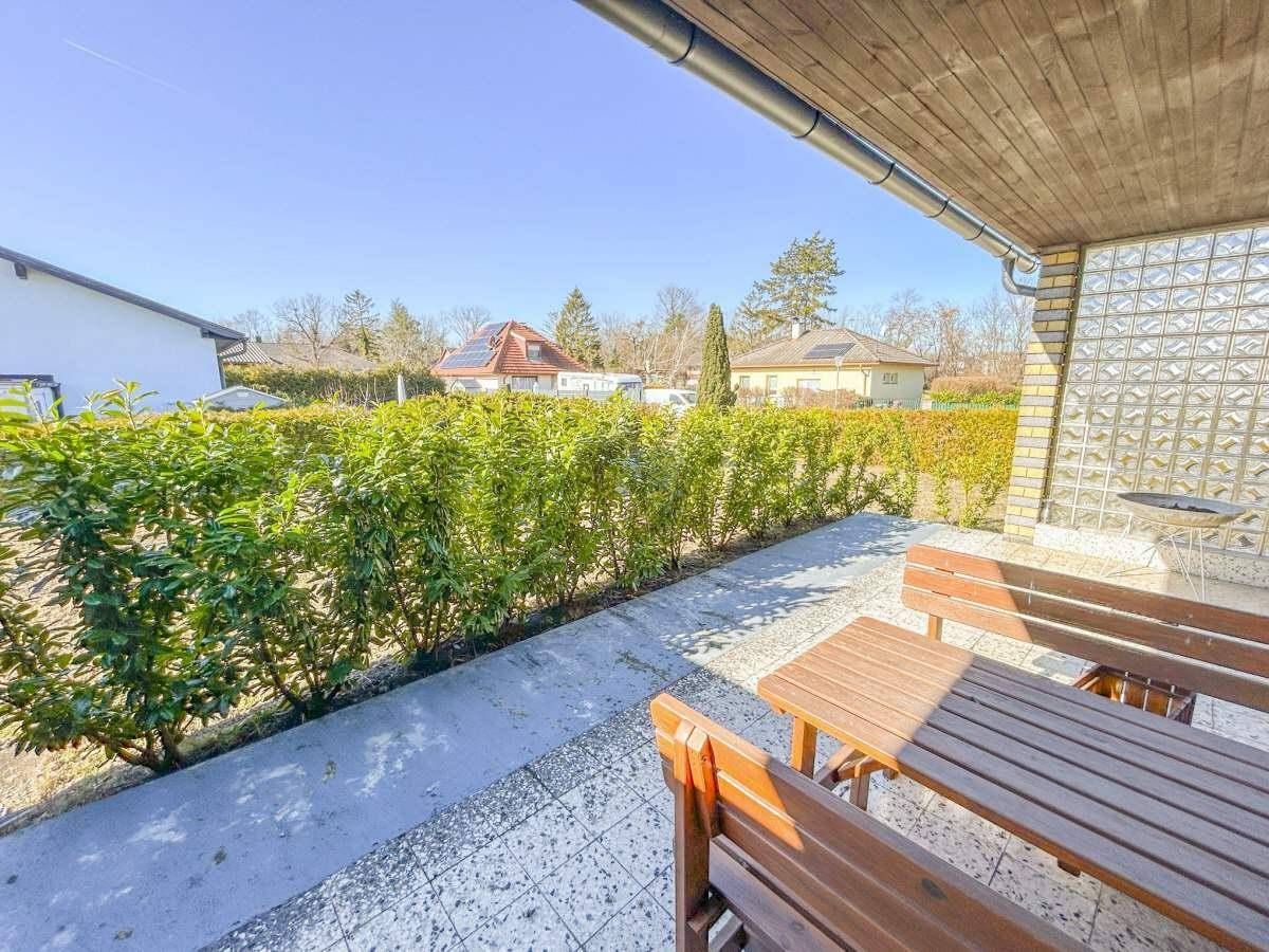Sonniger Terrassenbereich mit Holztisch und Blick auf den gepflegten Garten.