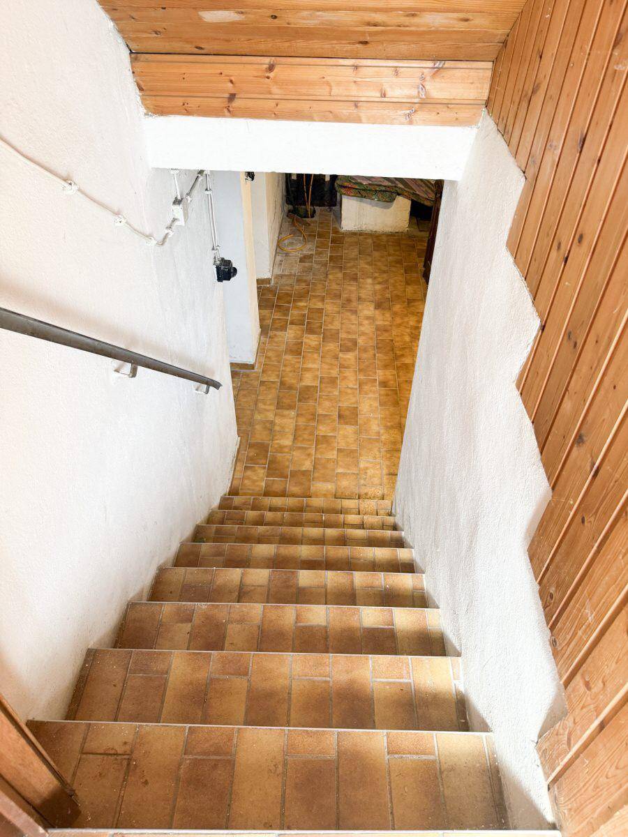 Treppe führt in den Keller mit Fliesenboden und Holzverkleidung.