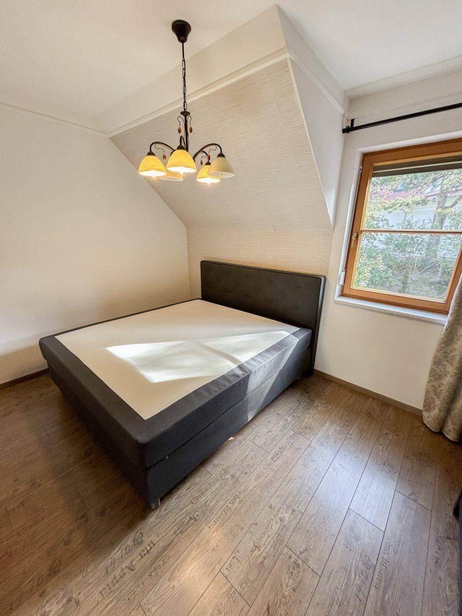 Schlafzimmer mit Doppelbett, Holzboden und Dachschräge.