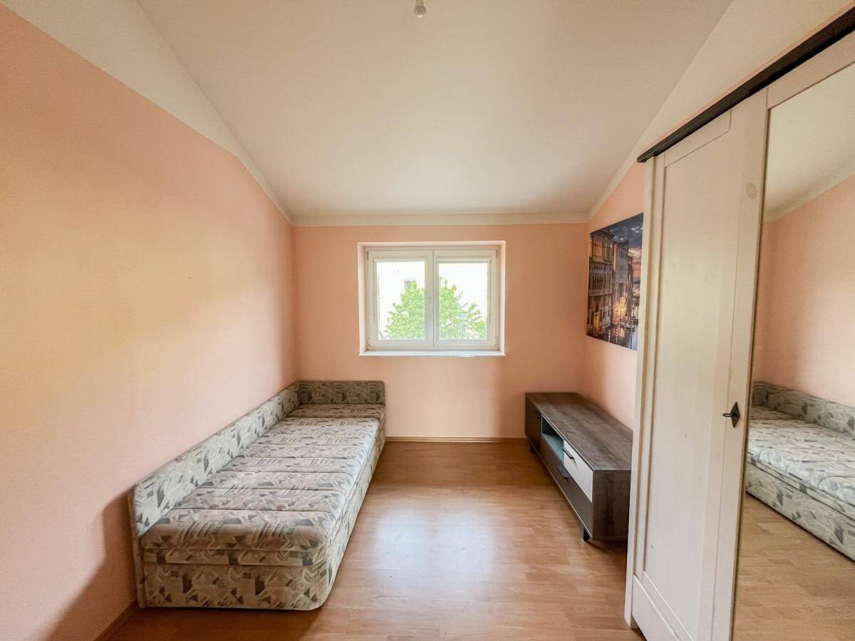Gemütliches Schlafzimmer mit Einzelbett, Fenster und hellrosa gestrichenen Wänden.