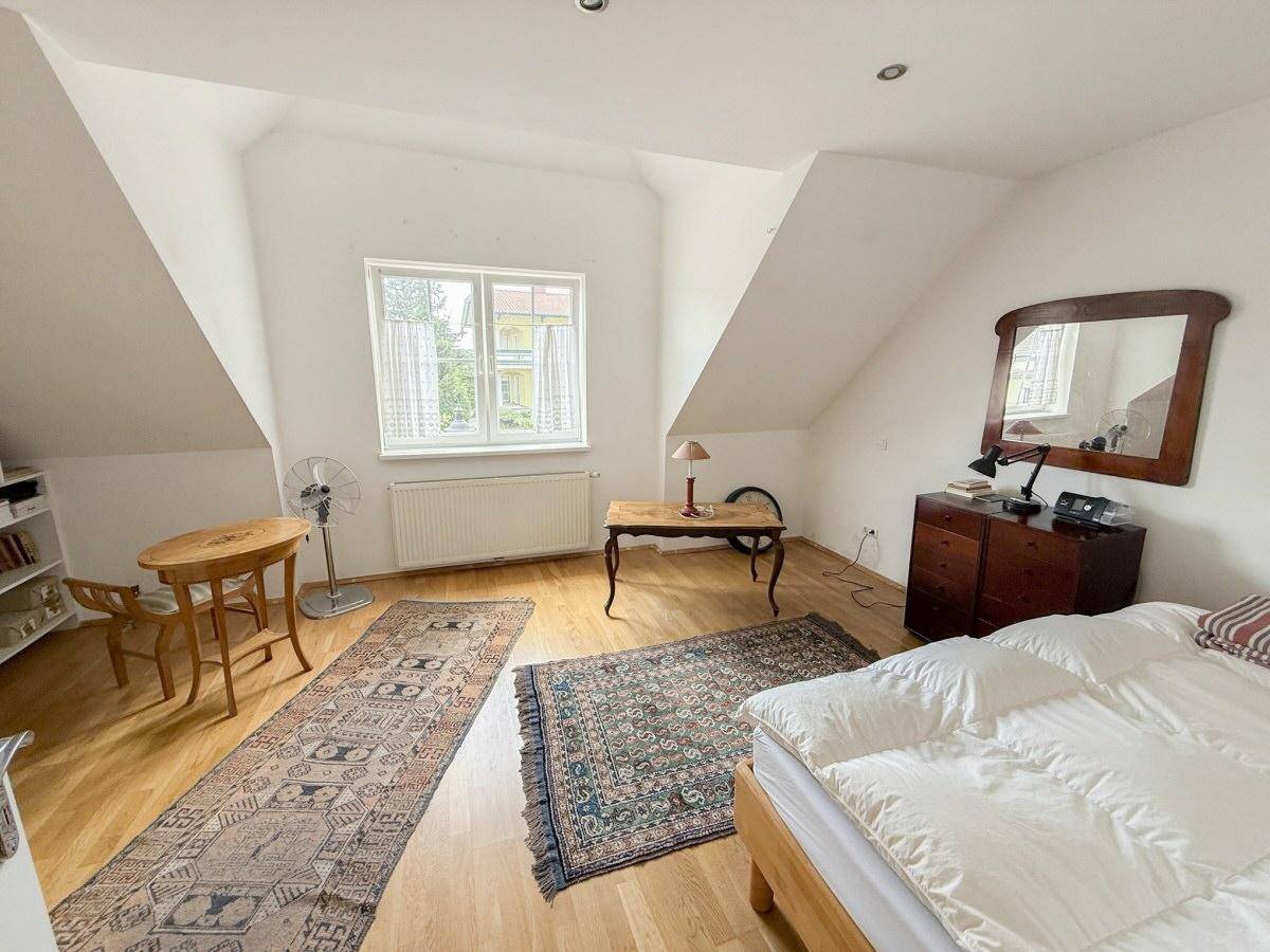 Gemütliches Schlafzimmer im Dachgeschoss mit Holzboden, Dachschrägen und einem Fenster.